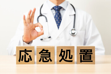 「応急処置」と書かれたブロックとOKサインをする医師