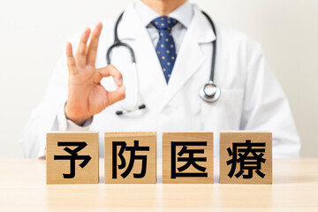 「予防医療」と書かれたブロックとOKサインをする医師