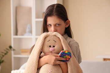 Sad girl with autistic disorder and toys at home