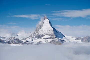 Landscape view of Matterhorn peak mountain in Switzerland cover with snow and clouded blue sky
