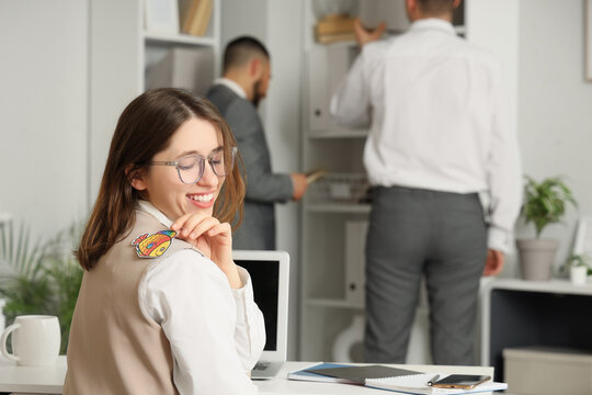 Young businesswoman with paper fish on her back in office. April Fools' Day celebration