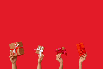 Female hands with different gift boxes on red background. Valentine's Day celebration