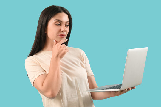 Thoughtful female programmer working with laptop on blue background