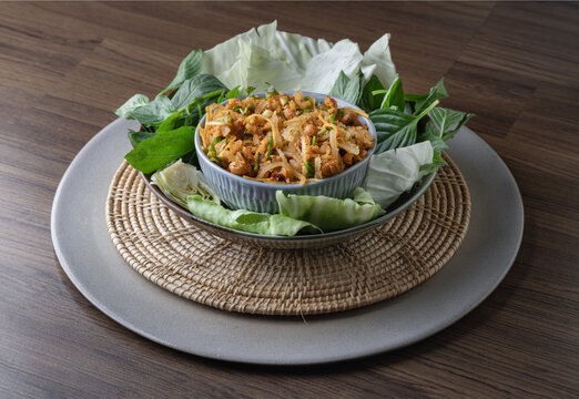 Enjoy a homemade fermented pork and Thai crispy fried rice salad, featuring crispy fried rice balls served with wild betel leaves (cha-plu leaves), ginger, peanuts, and lime juice. Yam Naem Khao Thot.