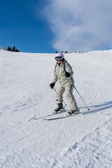 Obraz premium A woman skis down a snowy mountain on a sunny day, wearing a helmet and goggles. This image embodies winter sports, adventure, and an active lifestyle, perfect for promoting winter tourism.