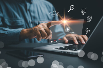 Online education, digital learning, and gaining knowledge are highlighted as person uses notebook to learn with e-learning icons, showing an online course video player on screen for modern students © sorapop