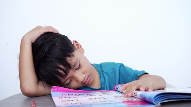 A tired Asian boy sleeping on a book while studying. Concept of academic pressure, exhaustion from homework, learning difficulties, and childhood education stress. 