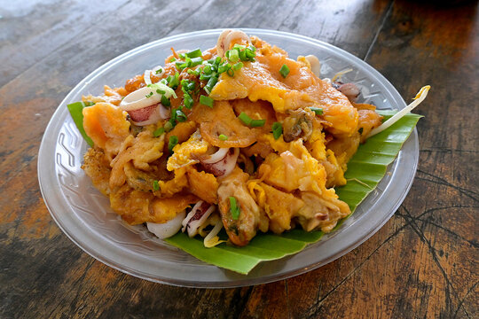 A variation of the popular Asian fried oyster omelette (Hoi Tod) served with mussels and squids on a banana leaf at a Thai floating market food stall