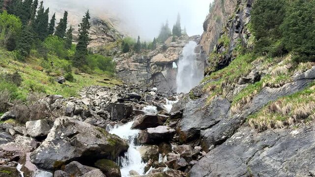 Tears of the Bars waterfall flowing through rocky terrain. Barskoon gorge natural landscape and natural wonder. Kyrgyzstan travel destination. Snow Leopard tears.