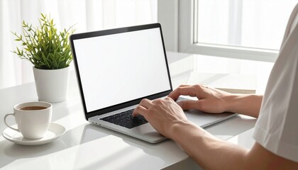 "Person typing on laptop with blank white screen, coffee cup and plant on desk, minimalist workspace near window symbolizing remote work and focus"