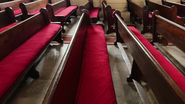 Rows of wooden pews and red pillow in Orthodox Cathedral