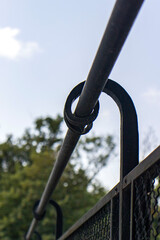 Naklejka premium Close-up detail of a hand-forged black wrought iron railing element on a sunny outdoor balcony
