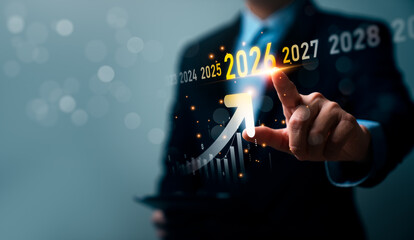 Business professional pointing at upward growth arrow highlighting year 2026 with financial chart, future planning timeline, and long term business growth strategy concept © Sutthiphong