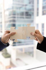 Two male hands connect white puzzle pieces, bring them together in perfect alignment, symbolizing connection between parties, collaboration, partnership, synergy. Business problem-solving, teamwork