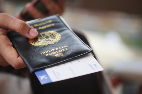 Holding a diplomatic passport and flight ticket in hand