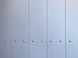 Obraz premium Light gray metal panel wall with vertical seams and rivets. Minimal industrial background texture with clean geometric lines, suitable for architecture, design, technology, mockups and branding projec