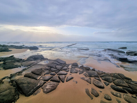 Rocks on Bar Beach Newcastle New South Wales Australia. Low tide early morning with a grey cloudy sky.