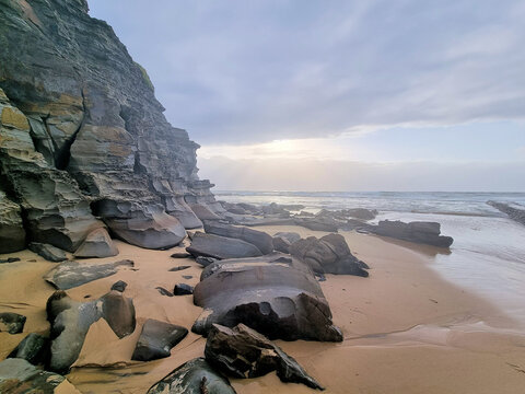 Eroded cliff face at Bar Beach Newcastle New South Wales Australia. Early morning with a grey cloudy sky.