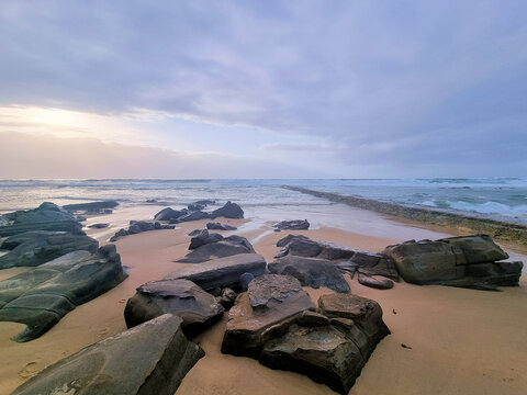 Rocks on Bar Beach Newcastle New South Wales Australia. Low tide early morning with a grey cloudy sky.