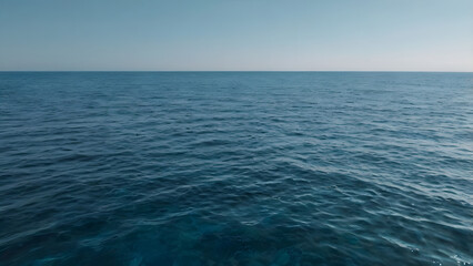 Obraz premium Infinite Horizon of the Open Ocean: The vast, serene expanse of the ocean stretches endlessly towards a clear, azure sky, reflecting the sun's gentle glow. 