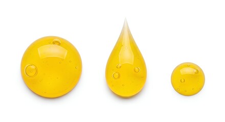 Fototapeta premium Three yellow droplets of different shapes and sizes on a plain surface from a direct viewpoint