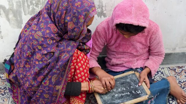 Elderly grandmother helping her grandchild learn writing on a slate in a rural Uttarakhand village home, highlighting education, care, and intergenerational bonding in simple mountain life.