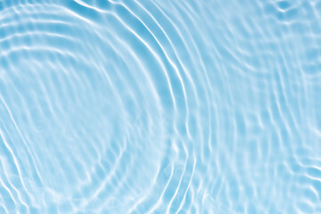 Blue water with ripples on the surface. Defocus blurred transparent blue colored clear calm water surface texture with splashes and bubbles. Water waves with shining pattern texture background.
