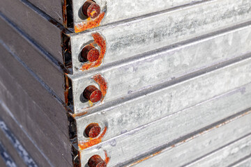 Stack of rusty metal beams with bolts displaying industrial decay