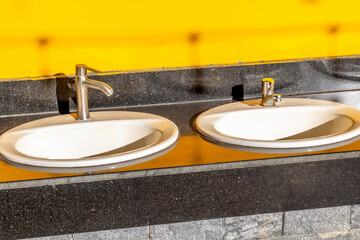 Double sink with bright yellow wall and modern faucets