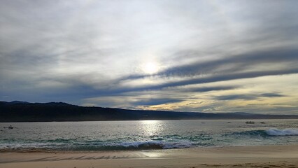 Calm Beach with Gentle Waves and Cloudy Sky at Sunrise