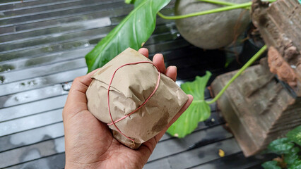 Hand Holding Traditional Indonesian Nasi Bungkus Wrapped in Brown Paper