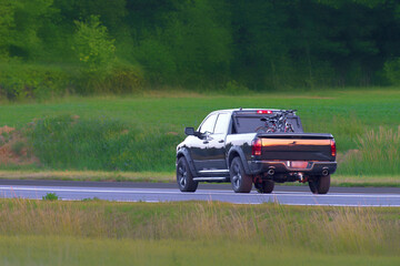 Fototapeta premium Automobile driving through countryside with mountain view