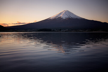 Mt Fuji in Japan, in predawn sunrise light, seen from across lake Kawaguchi, with ripples and reflection