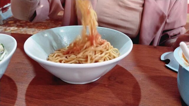 a woman eating Mie Bakso, or noodle soup with meatballs, one of the most popular cuisines in Indonesia, from street food, to restaurants