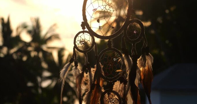 Dream catcher waving in the wind outdoors at green nature background in the evening.