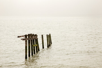Old Wooden Pier Remnant Extends Into Calm Sea Under Muted Dusk Sky
