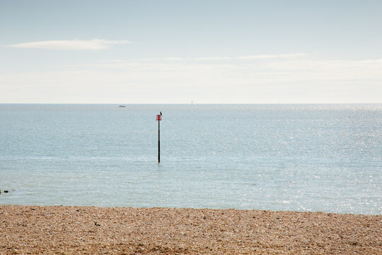 Peaceful Seascape With Pebble Beach, Horizon, And Red Beacon in Quiet Coastal Scene