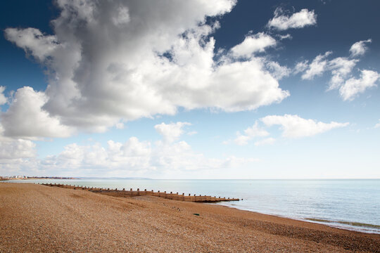 Peaceful Beach With Cloudy Sky Over Calm Sea and Wooden Breakwater at Dusk