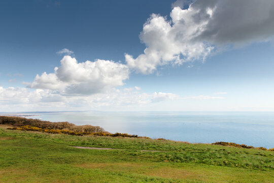 Coastal Landscape With Blue Sky and Puffy Clouds Over Calm Ocean