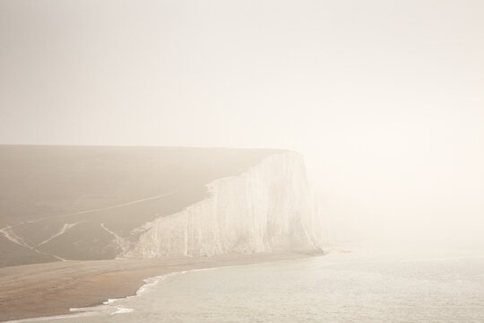 Majestic White Chalk Cliffs Over a Quiet Coastal Beach in Misty Weather