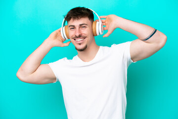 Naklejka premium Young caucasian handsome man isolated on blue background listening music