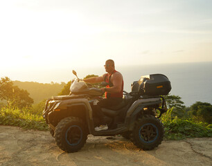 Fototapeta premium A man engages in extreme ATV riding on mountains in the evening