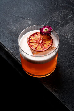 Vibrant orange craft cocktail with dried citrus and floral garnish