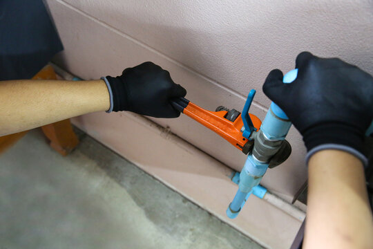 Plumber using a wrench to repair a water pipe. Concept of water pump maintenance fix water plumbing leaks drop or house bathroom service or cleaning clogged pipes is dirty or rusty.