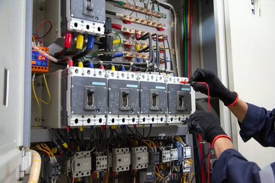Electrical service technician use electricity measuring tools equipment checking electric current circuit breaker terminal panel and cable wiring main power distribution board for maintenance system.