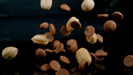MACRO: A mix of blanched hazelnuts and milk chocolate drops gets scattered.