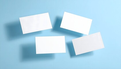 Four blank white business cards floating on a clean blue background with shadows