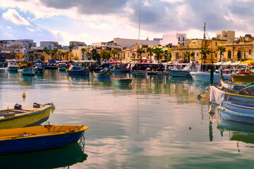 Marsaxlokk, Malta &ndash; Mediterranean atmosphere with colourful boats, market stalls and historic architecture along the promenade