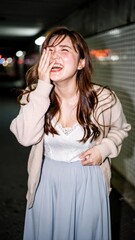 Fototapeta premium Joyful Japanese woman laughing heartily in a city tunnel at night