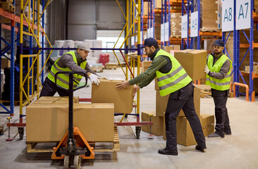 Naklejka premium Workers in warehouse loading boxes on pallet. Loaders prepare shipment with pallet jack and stack parcels. Safety vests and logistics ensure fast order flow. Concept of teamwork and logistics.